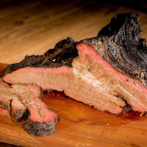 cooked sliced brisket on top of a cutting board to show how long to let brisket rest in cooler