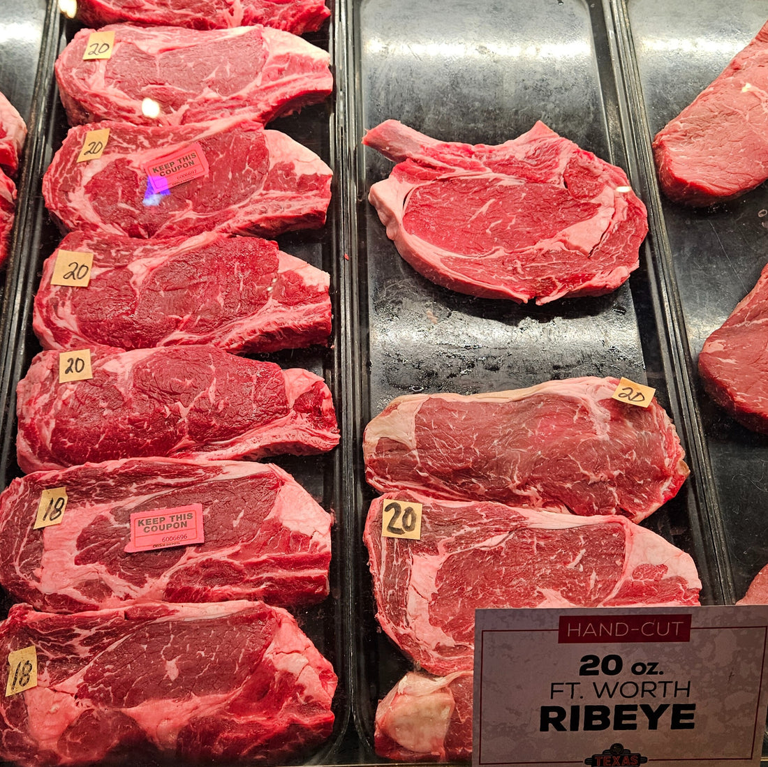 Raw ribeye steak cuts on trays with a label in front