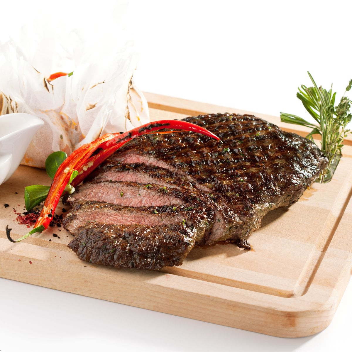 Sliced grilled flank steak over wood chopping board