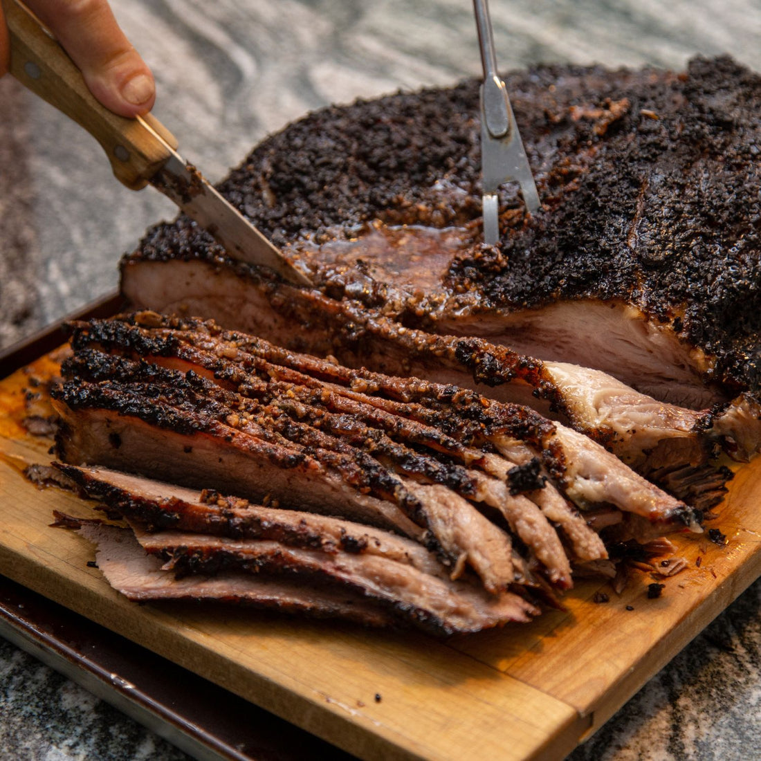 cooked brisket being sliced with the best brisket knife