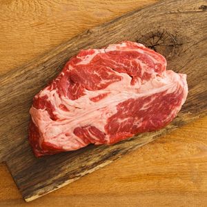 raw chuck wagon steak on a wood cutting board to show what is a chuck wagon steak