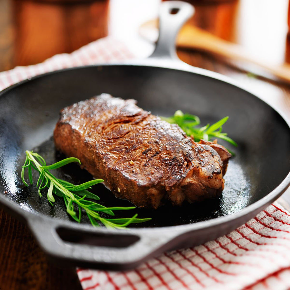 Cooked new york strip steak with fresh herbs on skillet