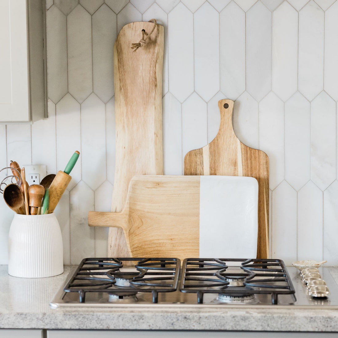 three wooden cutting boards displayed behind a stove to show how to display cutting boards on kitchen counter