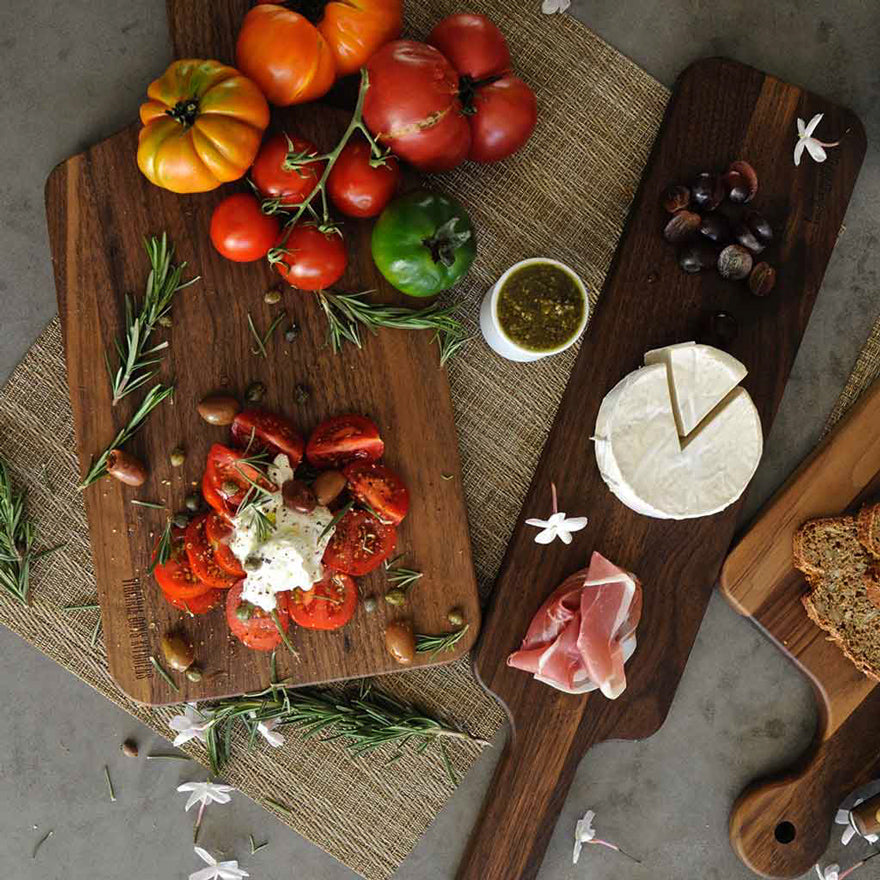 three walnut cutting boards with an assortment of chopped foods