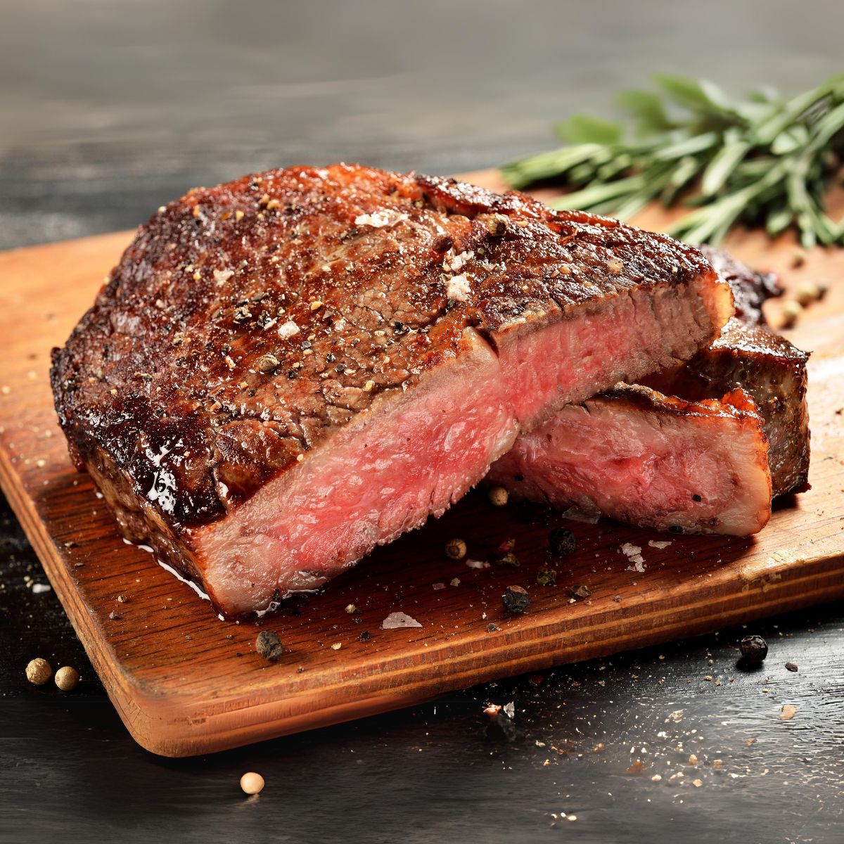 Medium rare ribeye steak in half over a wood cutting board