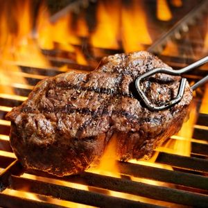 close-up view of a steak on a flaming grill to show what is a sizzler steak